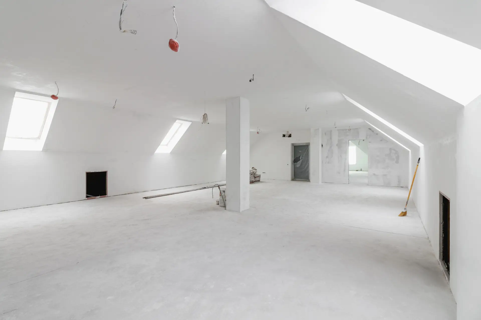 Spacious empty rooms in the attic floor after filling out the work on the wall and ceiling.
